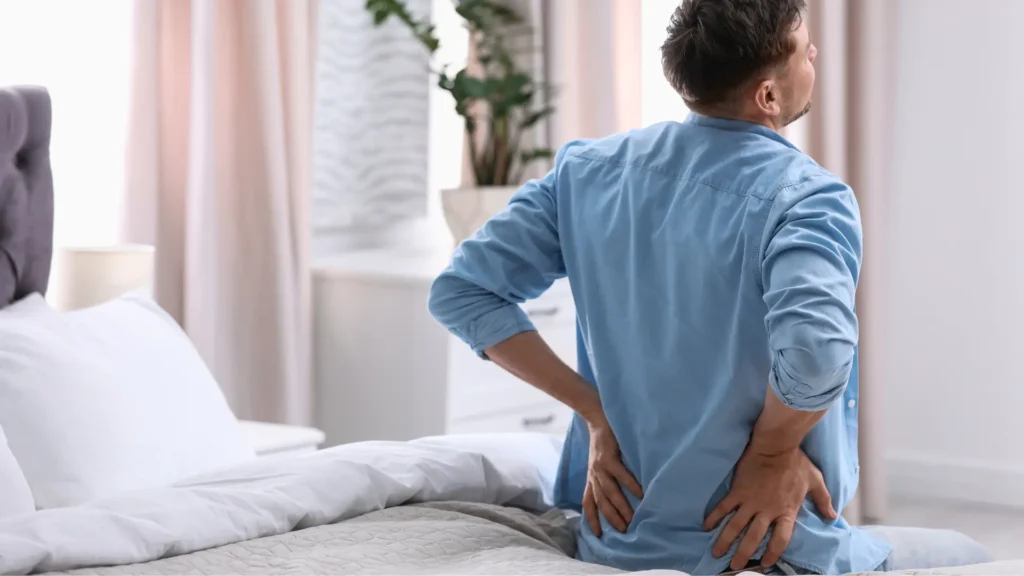 Man sitting on bed with back pain